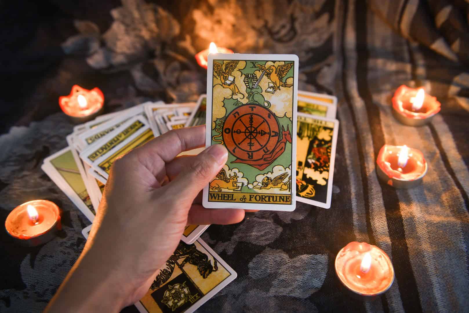Hand holding tarot card with candlelight on the darkness background for Astrology Occult Magic illustration / Magic Spiritual Horoscopes and Palm reading fortune teller concept